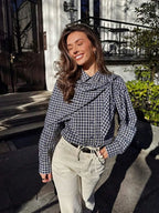 Navy plaid scarf-tie shirt styled with cream trousers